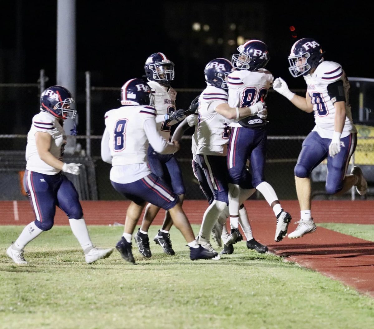 Rebels players celebrate with Chaz Evans (No. 80) after he scored his first touchdown against Crescent City. 