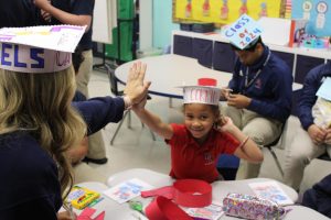 Seniors and kindergarten students made paper graduation hats together. 