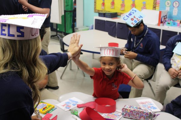 Seniors and kindergarten students made paper graduation hats together. 